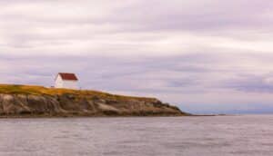 white and red wooden house near sea during daytime
